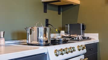 A kitchen with a stove, a kettle, and a coffee machine.