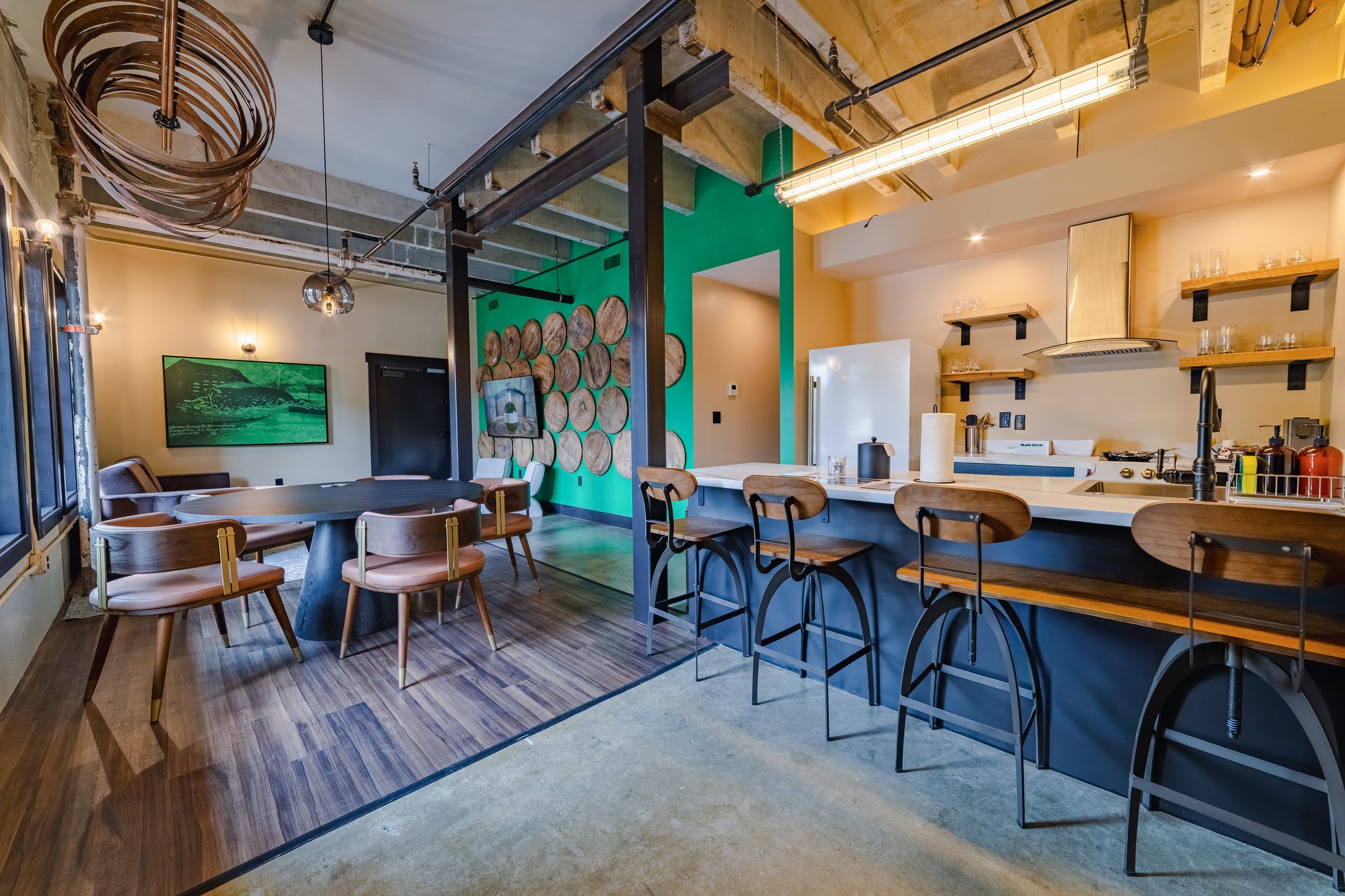 Un espace bar moderne avec une table ronde, des tabourets de bar et un mur d’accent vert agrémenté de décorations en bois.