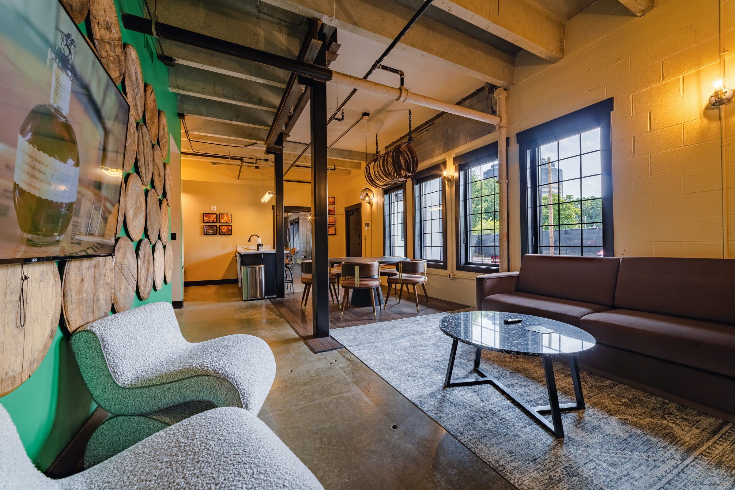 Un intérieur moderne comprenant un coin salon, une cuisine et de grandes fenêtres.