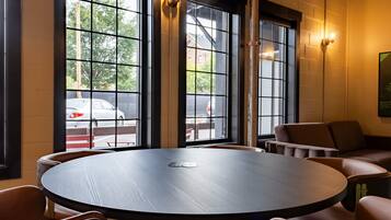 A round table with chairs in a room with large windows and a view of the street outside.