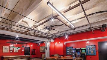 A room with red walls, exposed ceiling pipes, and a pool table.