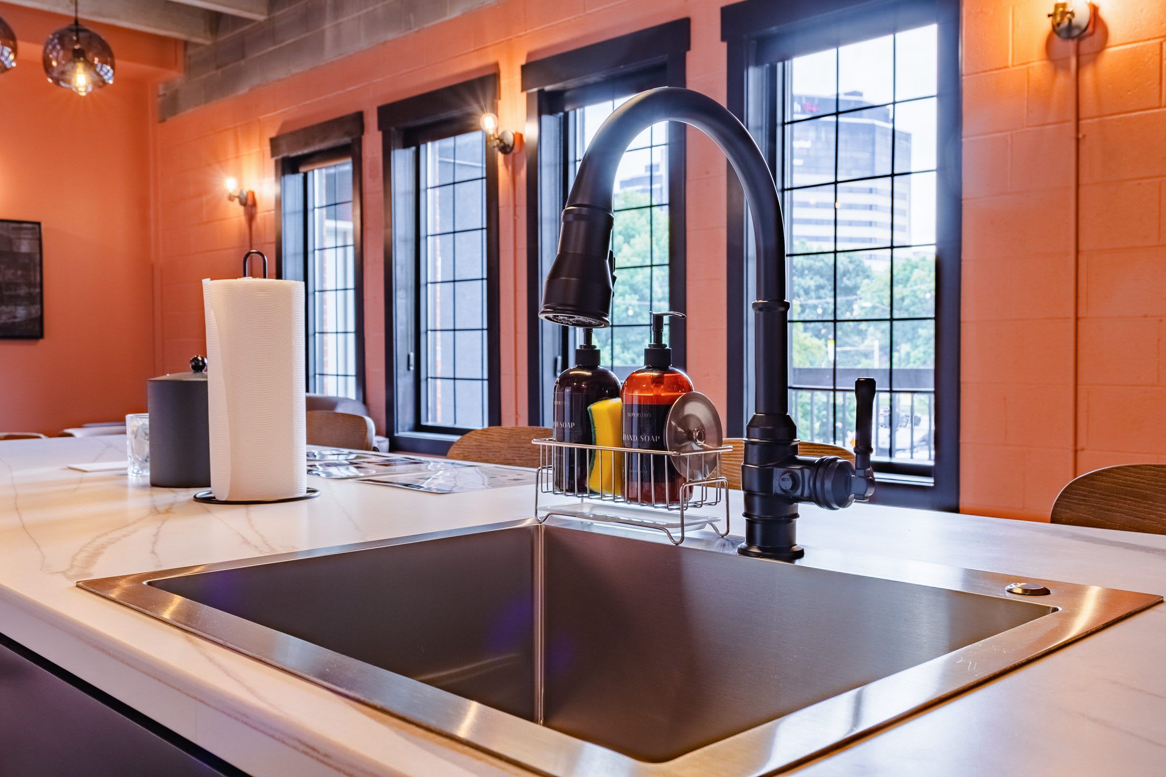Una cucina moderna con lavello in acciaio inossidabile, porta asciugamani e dispenser per sapone.