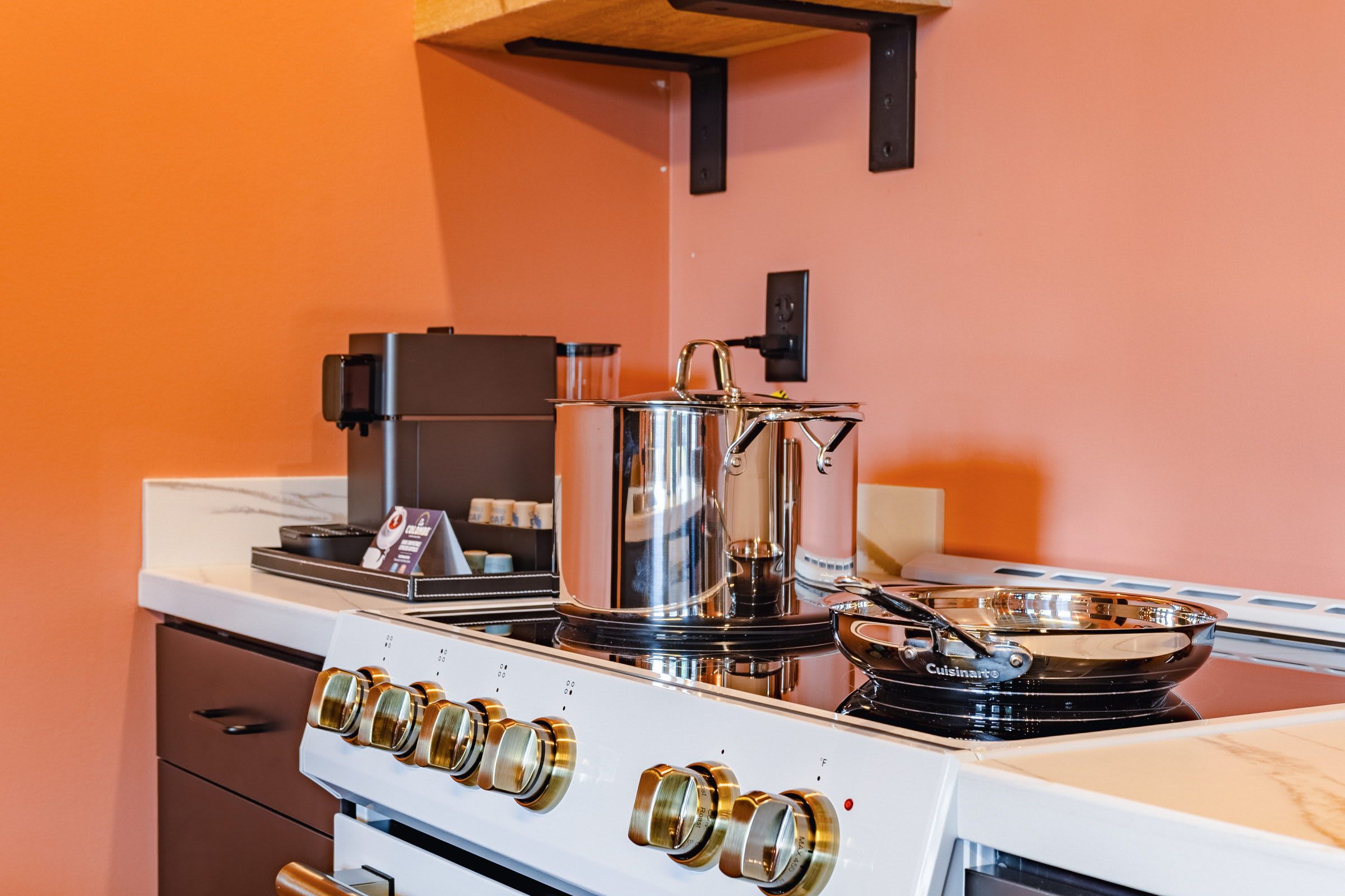 A kitchen with a white stove, a coffee maker, and a pot on the stove.