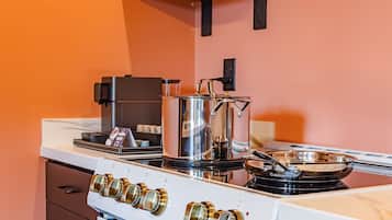 A kitchen with a white stove, a coffee maker, and a pot on the stove.