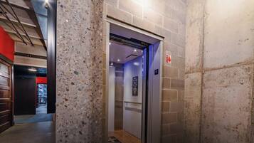 Um elevador com uma placa indicando o andar, um sinal de segurança contra incêndio e um corredor com parede vermelha e uma porta.