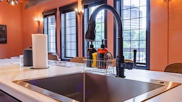 A modern kitchen with a stainless steel sink, a paper towel holder, and a soap dispenser.