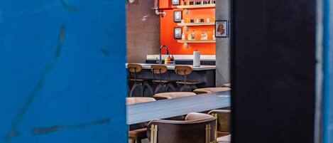 Interior de restaurante con pared de ladrillo, estanterías anaranjadas y sillas de madera.