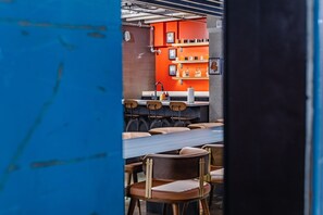 Interior de restaurante con pared de ladrillo, estanterías anaranjadas y sillas de madera.