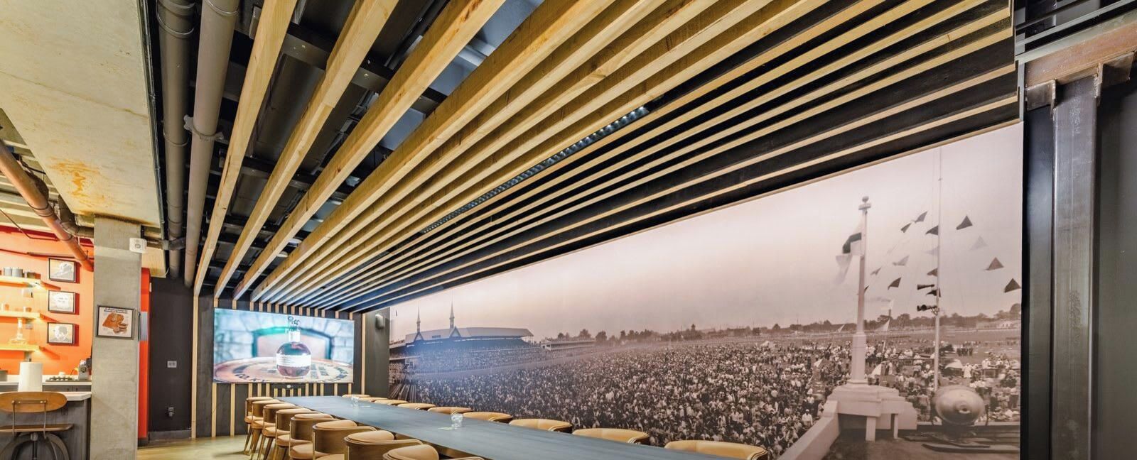 Un salón de conferencias con una larga mesa, sillas y una pantalla grande que muestra una multitud.