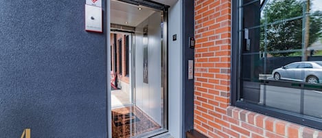 En hotellentrél med en glasdörr, en brandlarm och en bil som syns genom fönstret.