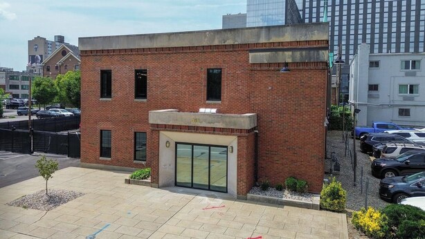 Edificio in mattoni con un ingresso numerato, parcheggio e edifici più alti adiacenti.