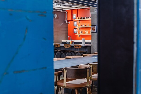 L’intérieur d’un restaurant avec un mur en briques, des étagères orange et des chaises en bois.