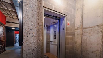An elevator with a sign indicating the floor level, a fire safety sign, and a corridor with a red wall and a door.