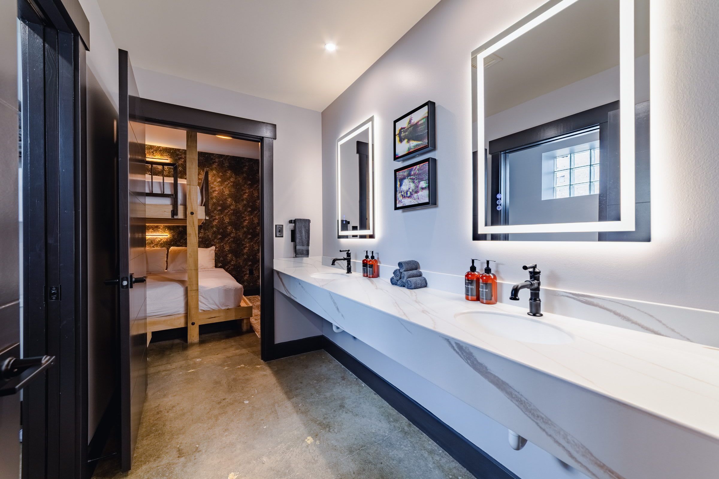 A modern bathroom with a large mirror, a vanity with a marble countertop, and a shower area visible through a glass door.