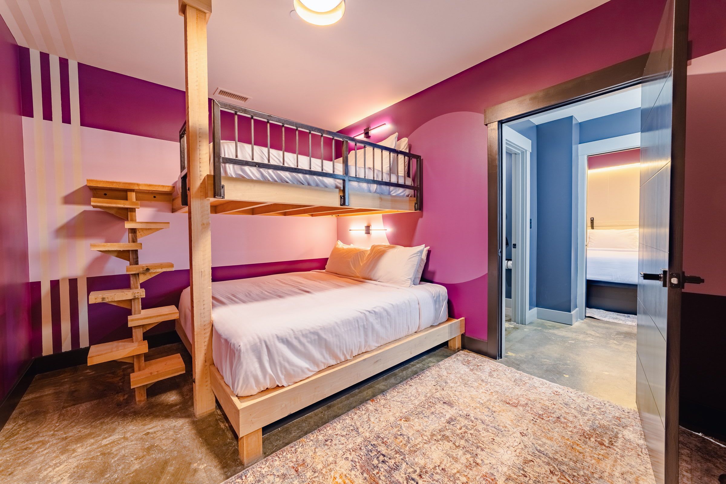 A bunk bed with a wooden ladder, a white mattress, and a pink wall.