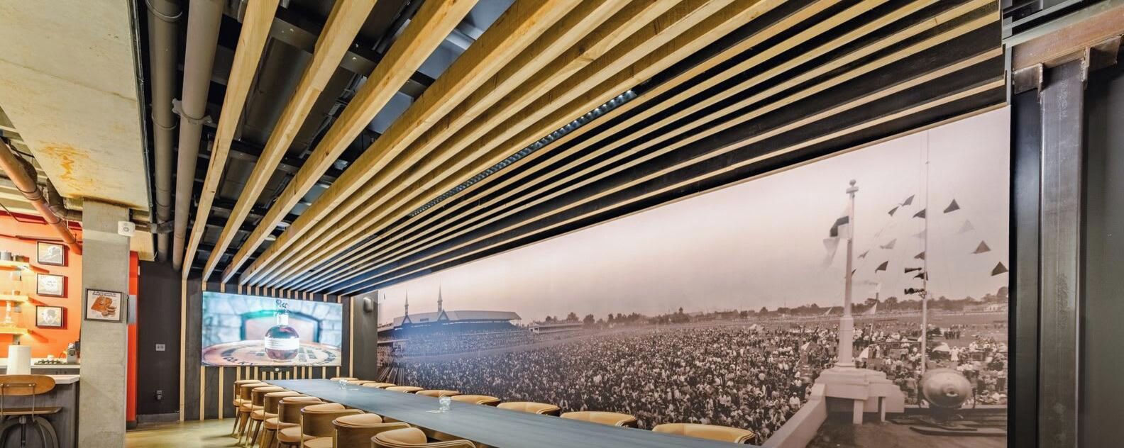 A conference room with a long table, chairs, and a large screen displaying a crowd.