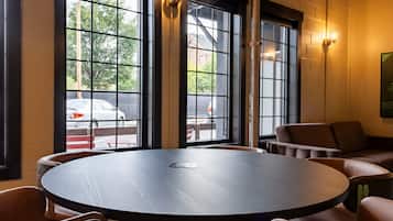 A round table with chairs in a room with large windows and a view of the street outside.