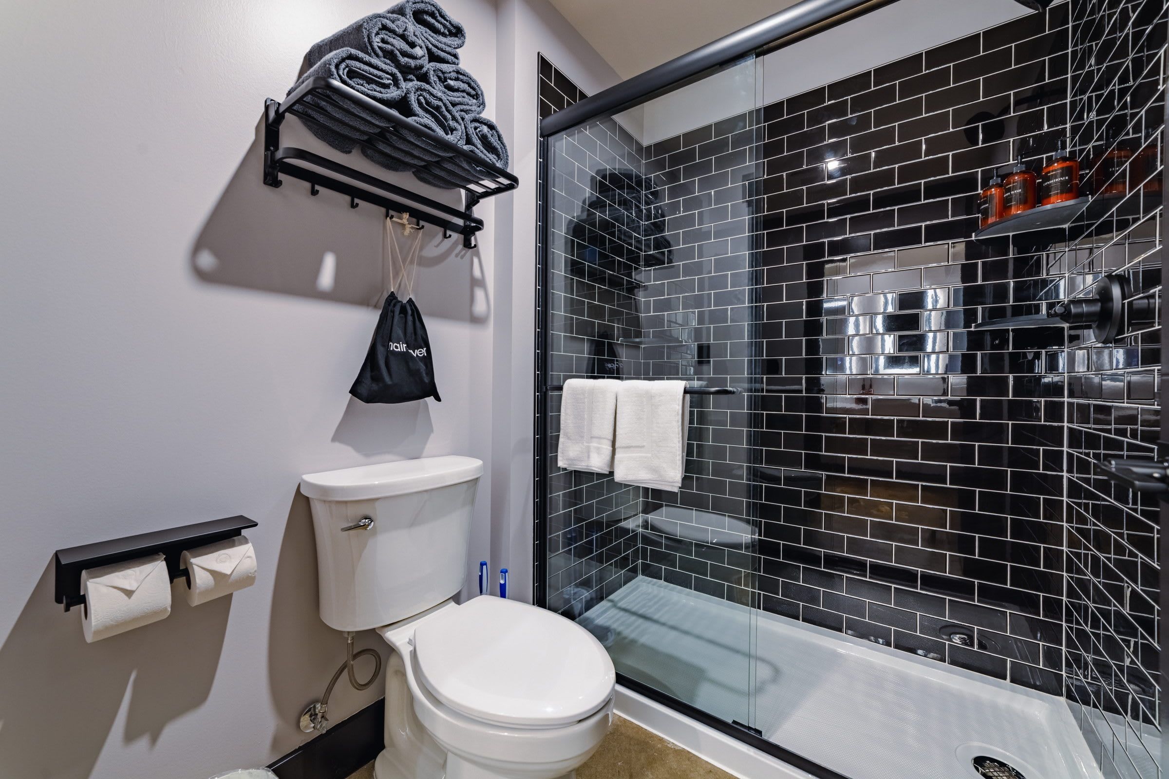 A modern bathroom with a toilet, a glass shower enclosure, and a towel rack.
