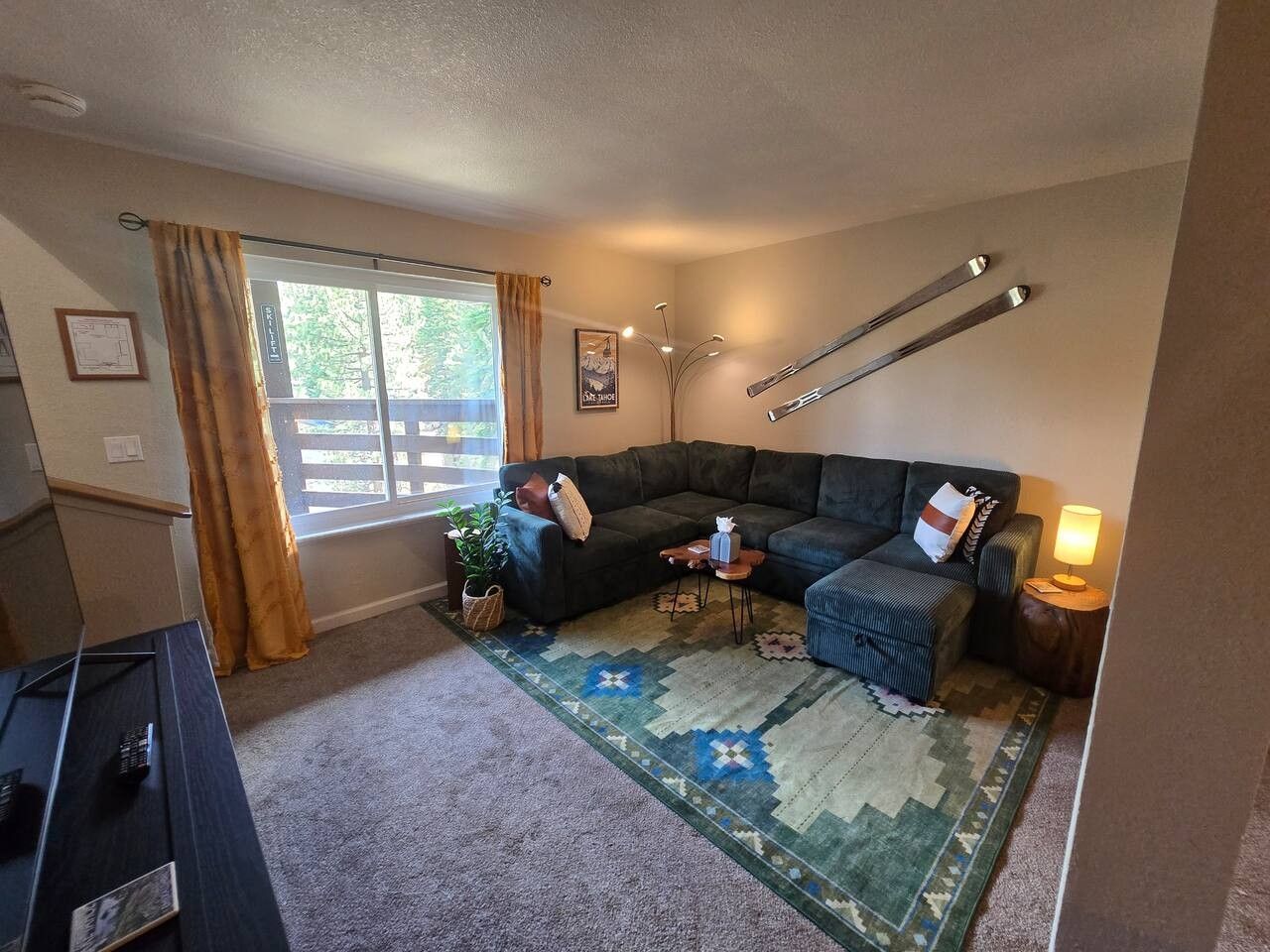 Un salon avec un canapé, une petite table, une lampe et une fenêtre avec des rideaux.