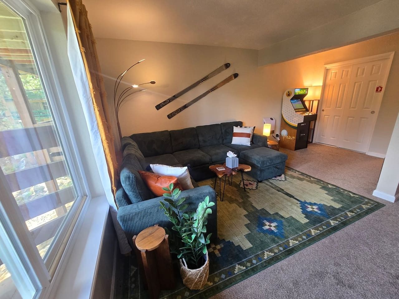 Un salon avec un canapé, une table basse, un tapis et une porte au fond.