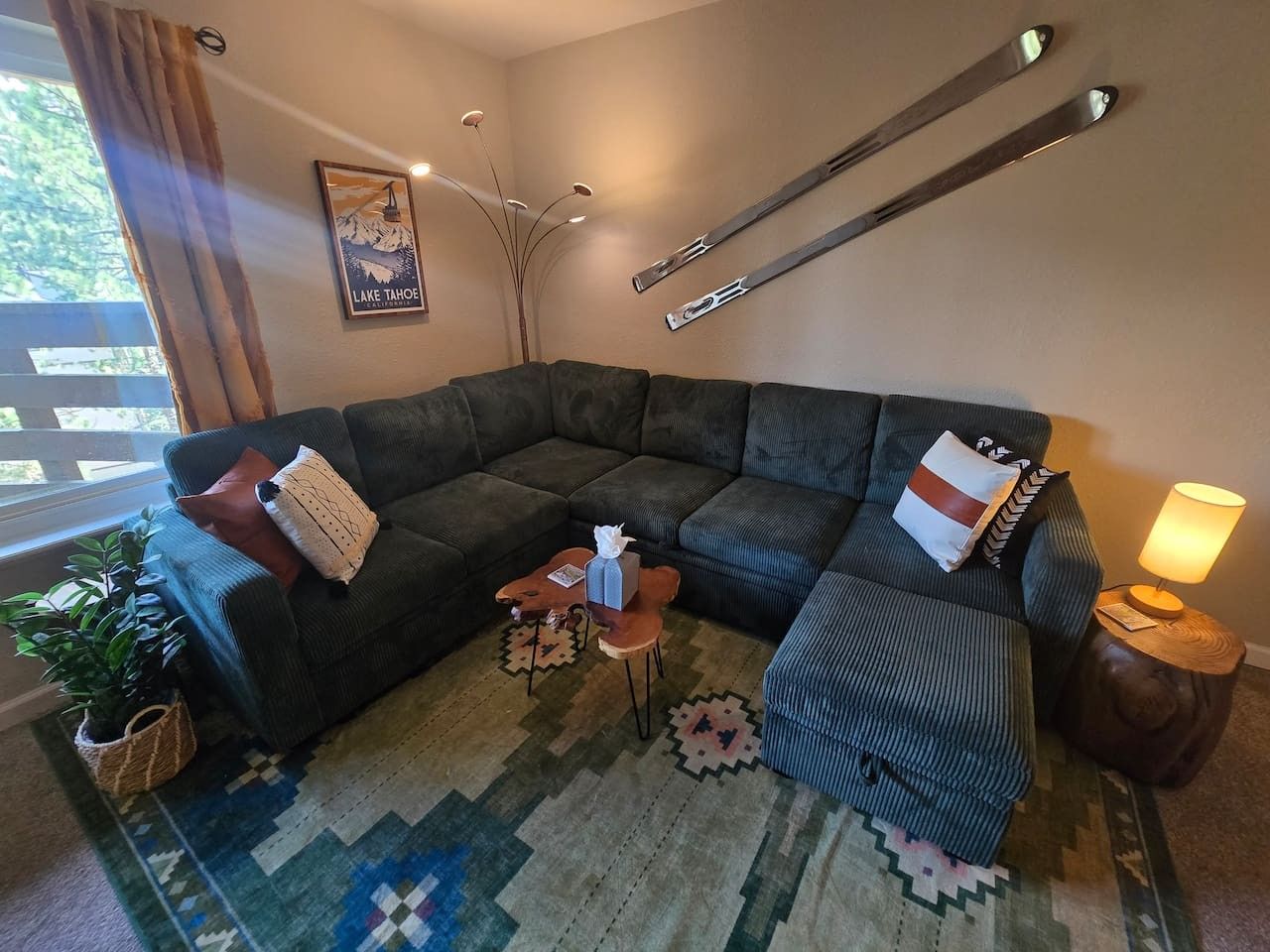Un salon chaleureux avec un canapé d’angle, une petite table basse, une lampe et une affiche accrochée au mur.