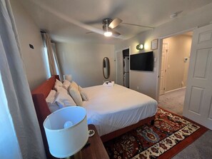 A bedroom with a bed, a ceiling fan, a television, and a door leading to another room. - Tahoe Condo | Arcade & Fireplace | Sleeps 6 (Stateline)