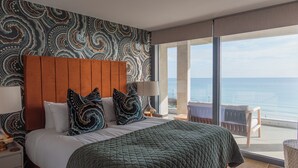 Een hotelkamer met een groot bed, uitzicht op de zee en een kamerwand met een patroon.