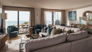 Een moderne woonkamer met een grote bank, fauteuils en een eethoek.