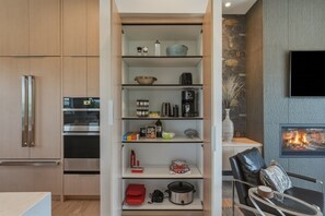 Eine moderne Küche mit eingebauten Geräten, ein Essbereich mit einem schwarzen Ledersessel und ein Kamin.