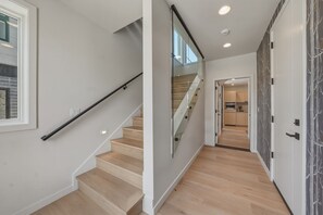 Eine Treppe mit Holzboden und Glastrennwand, die zu einem Küchenbereich führt.