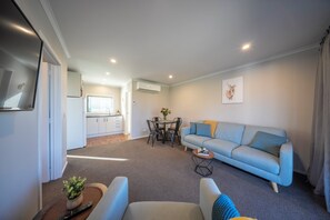 Ein modernes Wohnzimmer mit Sofa, Sesseln, einem Couchtisch und einem Essbereich mit Tisch und Stühlen.