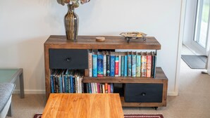 A wooden bookshelf with multiple compartments, a vase with dried plants, and a small decorative plate on top.