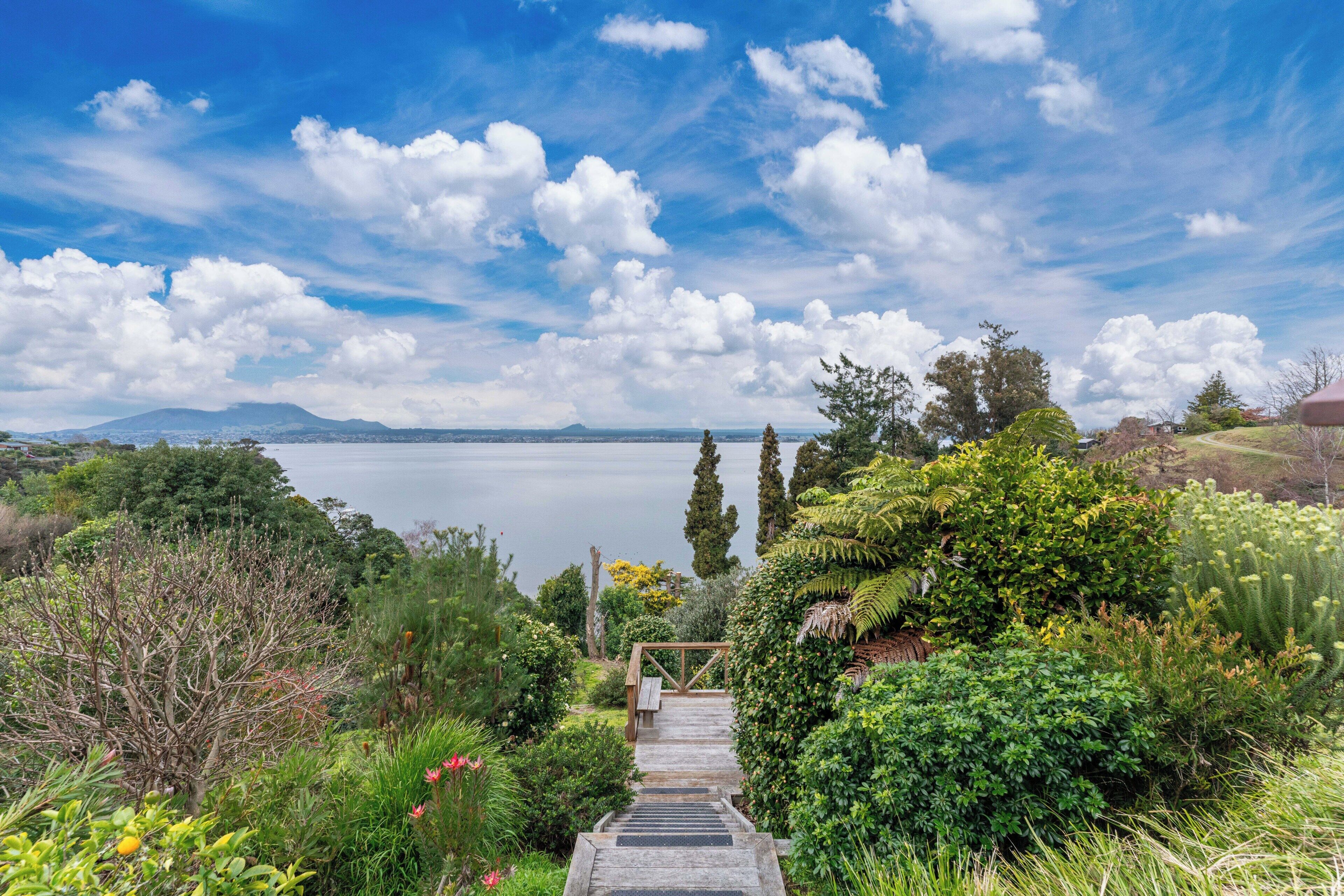 A wooden staircase leading to a deck overlooking a body of water with mountains in the distance.