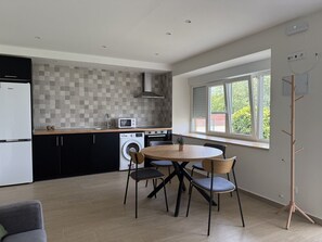 Una cuina moderna amb zona de menjador, rentadora i una finestra gran.