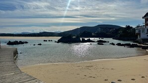 A beach with a wooden walkway, rocky outcrops in the water, and a mountain in the background. - La Mimosa Apartment 2607 (San Miguel de Meruelo)