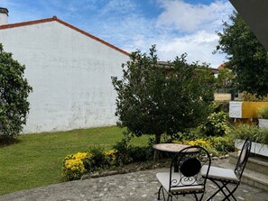 A courtyard with a white wall, a round table, two chairs, and a tree. - La Mimosa Apartment 2607 (San Miguel de Meruelo)