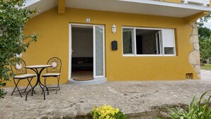 A yellow building with a balcony, a door, and a small outdoor seating area with two chairs and a table. - La Mimosa Apartment 2607 (San Miguel de Meruelo)