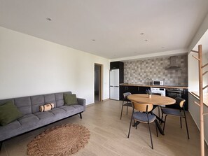 Ein stilvoller Wohnbereich mit einer Couch, Esstisch, Stühlen und einer Küchenzeile mit Geräte.