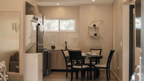 A compact kitchen with a dining area, a built-in refrigerator, and a window providing natural light. - Luxury Apartment with Breathtaking Mountain Views | Pet-Friendly (Alto Boquete)