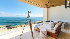 Een slaapkamer met een groot bed, een telescoop en uitzicht op de oceaan.