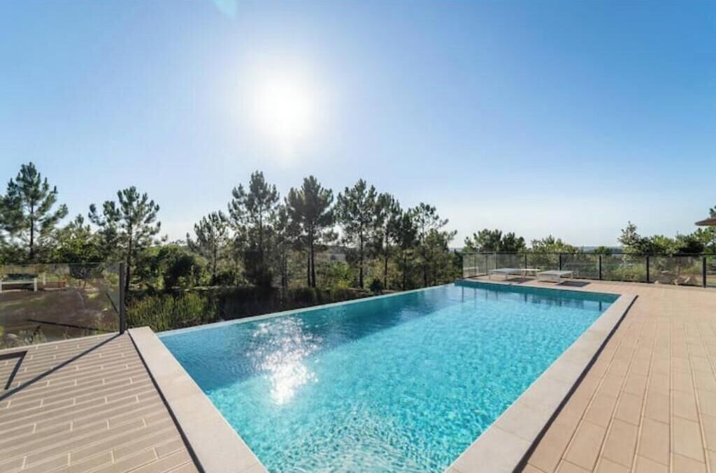 Une piscine rectangulaire à l’eau d’un bleu limpide, entourée d’une terrasse carrelée.