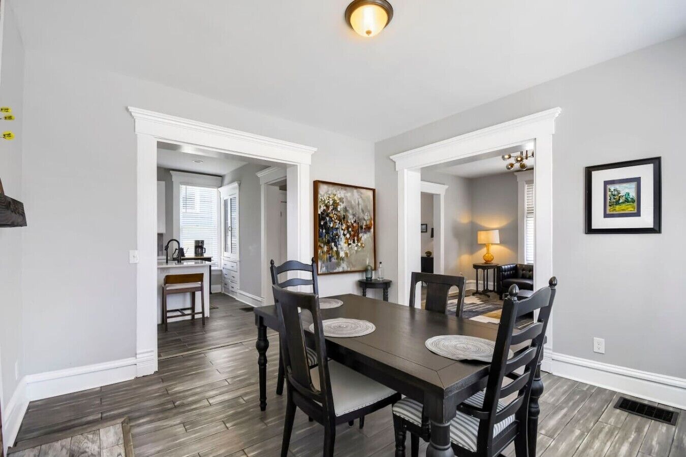 A dining area with a wooden table, black chairs, and a painting on the wall.