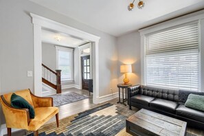 A living room with a sofa, a chair, a lamp, and a coffee table. - 3BR Victorian in Old Oaks, near German Village (Columbus)
