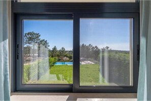 Eine Glasschiebetür mit Blick auf eine Wiese und Bäume.