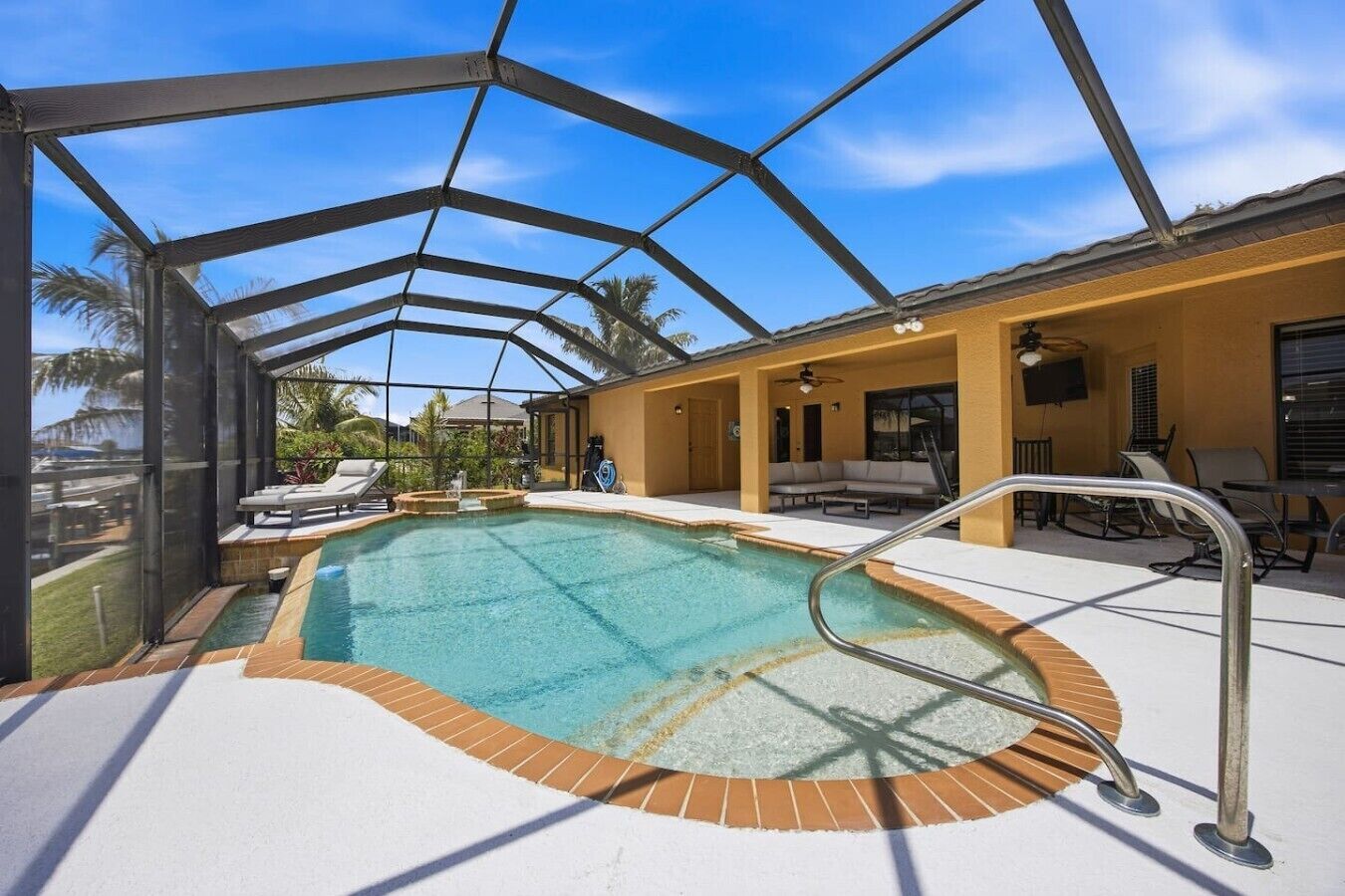 A covered outdoor swimming pool with a sunshade, lounge chairs, and a patio area.