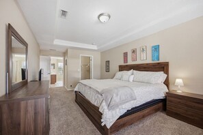 Ein Schlafzimmer mit einem großen Bett, einem Schminktisch, einem Nachttisch und einer Deckenleuchte.