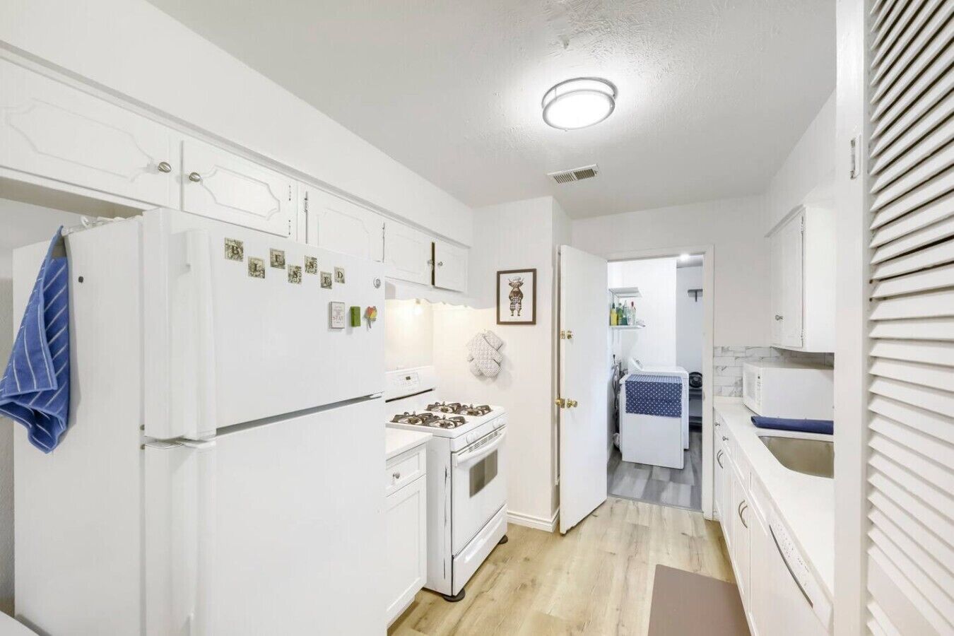 A modern kitchen with white cabinets, a stove, and a refrigerator.