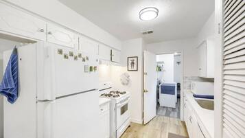 A modern kitchen with white cabinets, a stove, and a refrigerator.