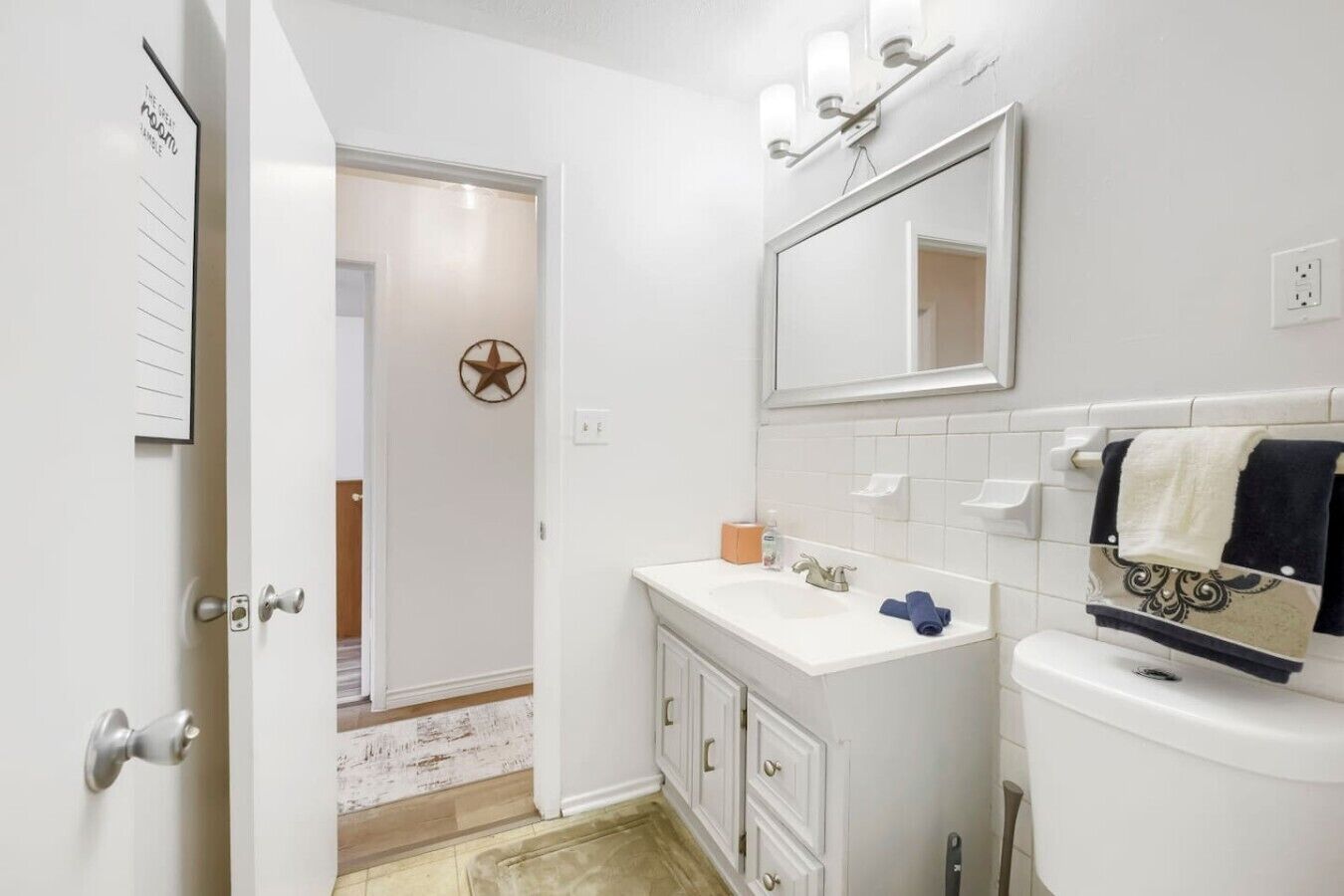 Une salle de bain avec un lavabo blanc, un miroir au-dessus du lavabo, des toilettes et un porte-serviettes avec des serviettes.