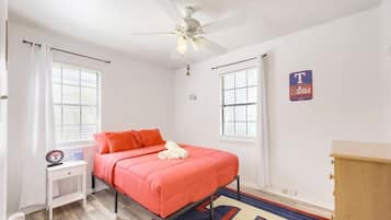 A bedroom with a bed, a nightstand, a dresser, a ceiling fan, and a window with blinds.